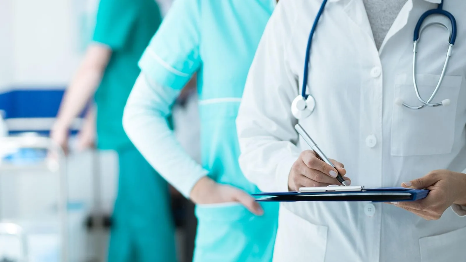 Doctor with a stethoscope holding a clipboard, with nursing staff